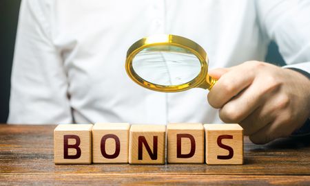 A man examines the inscription Bonds with a magnifying glass. Assessment of the value and profitability of securities