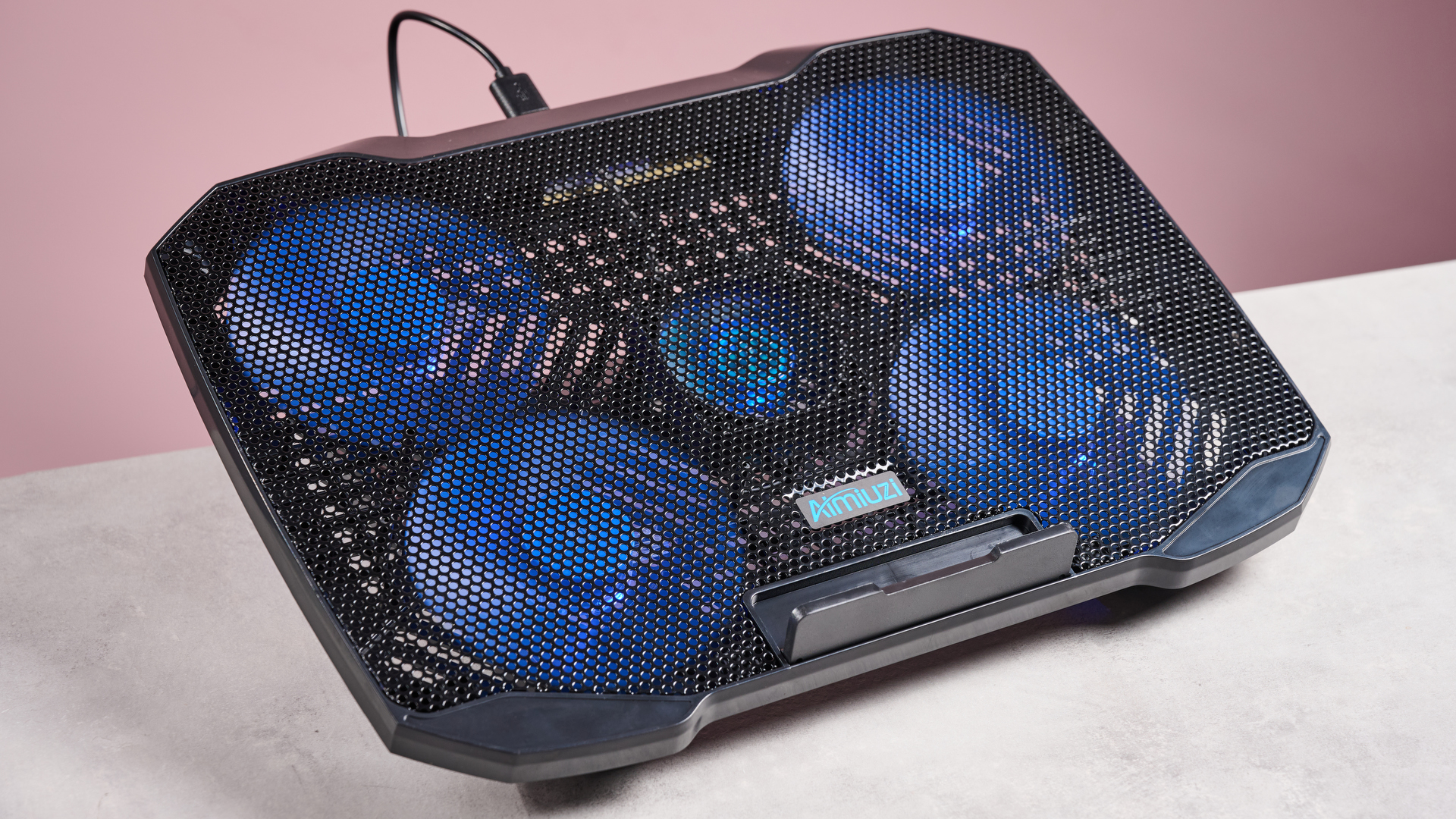The Aimuzi F2 Plus laptop cooling pad at a 3/4s angle in front of a pink background.
