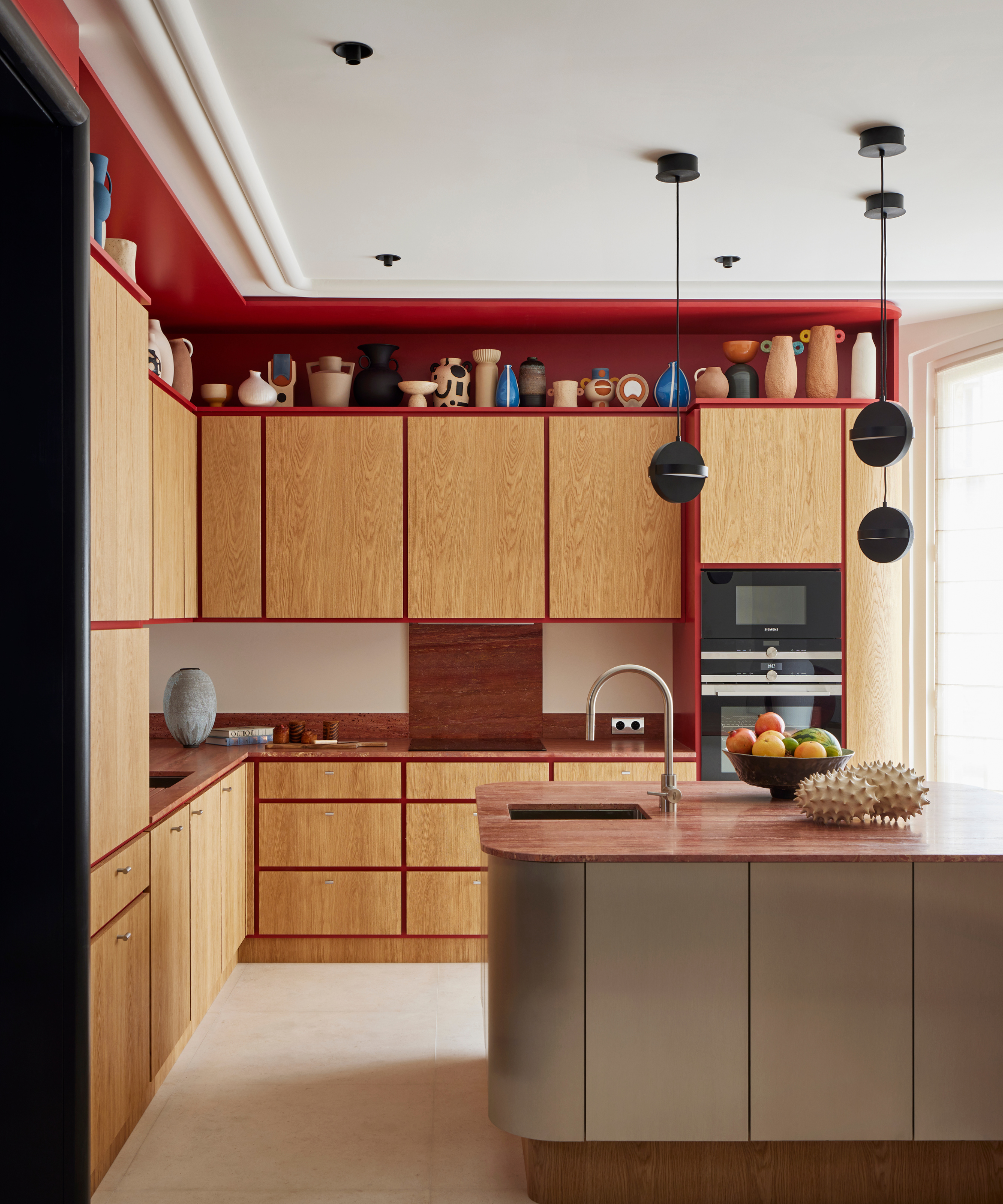 Red and wood tone kitchen with island and round drop pendant lighting