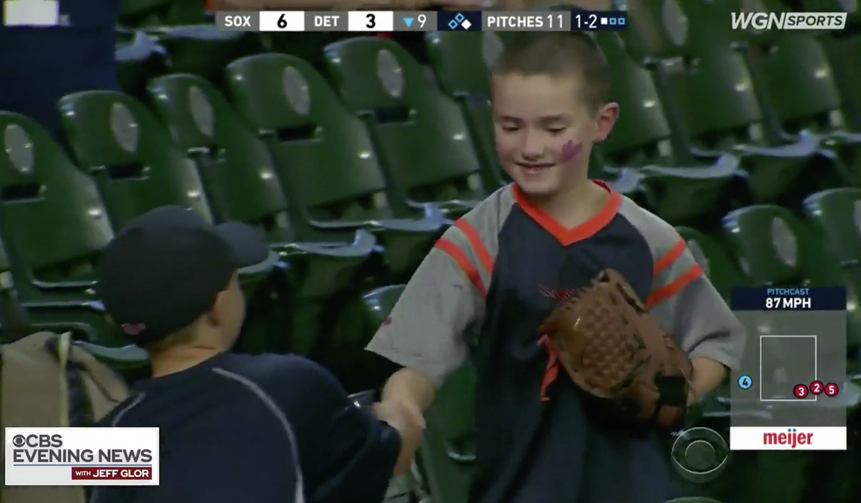 Boy shakes hand of boy who gave him foul baseball.