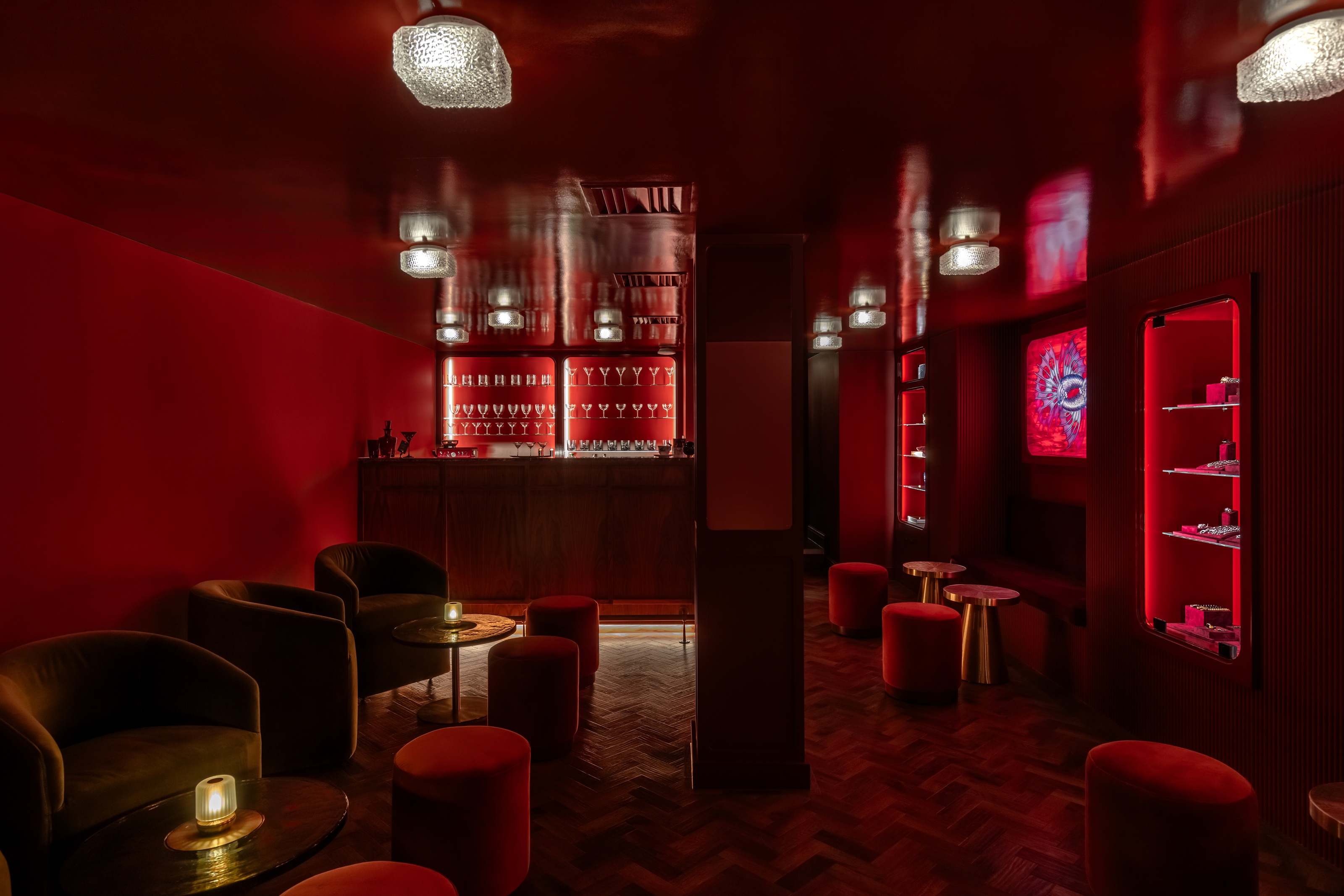 a red cocktail bar with red and gold furnishings and a wall of cocktail glasses
