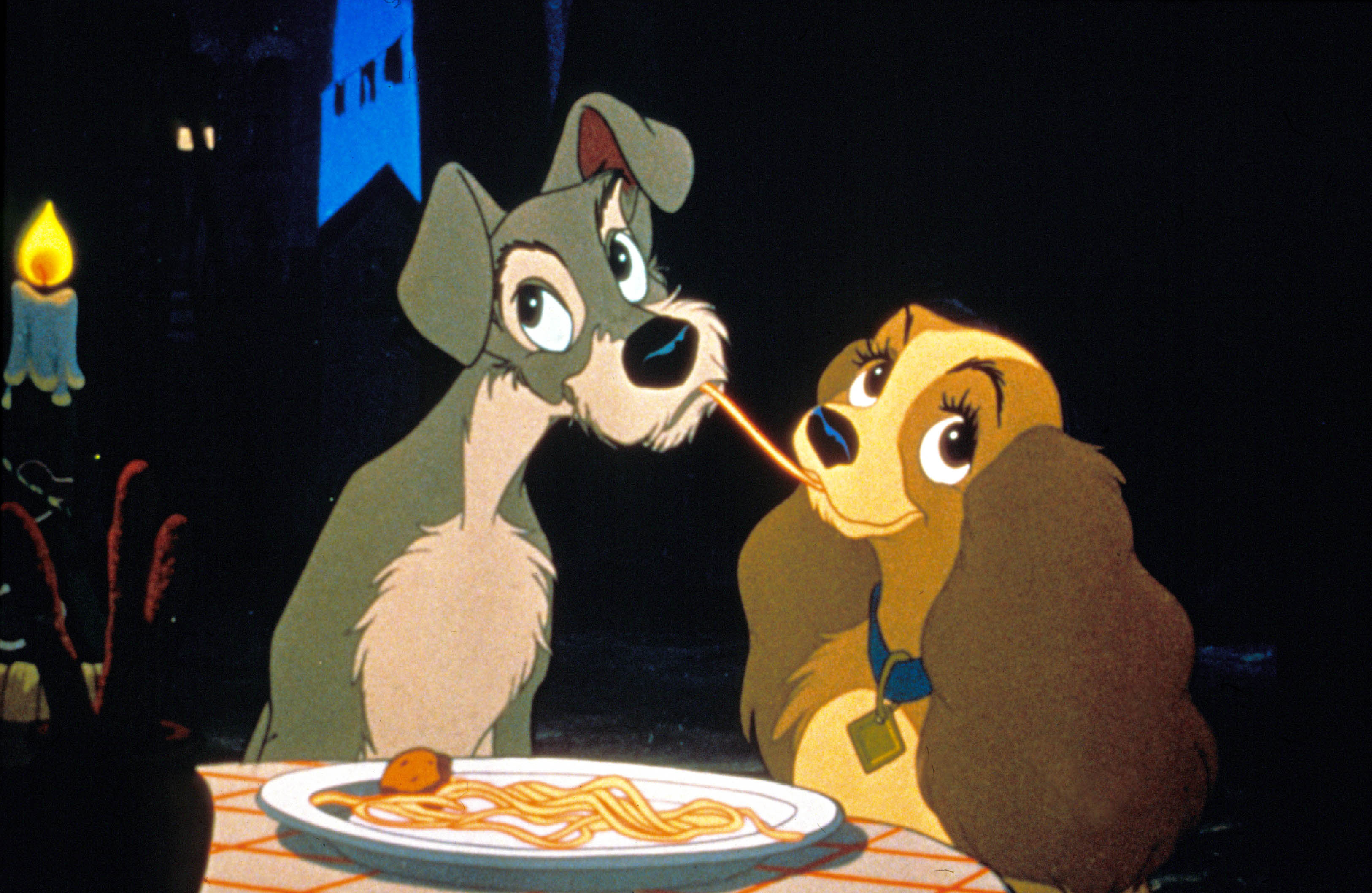 Animated still from Lady and the Tramp showing Lady and Tramp sharing a strand of spaghetti by candlelight.