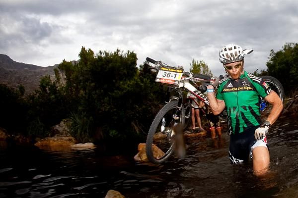 Mixed category race leader Barti Bucher carries his bike across a river