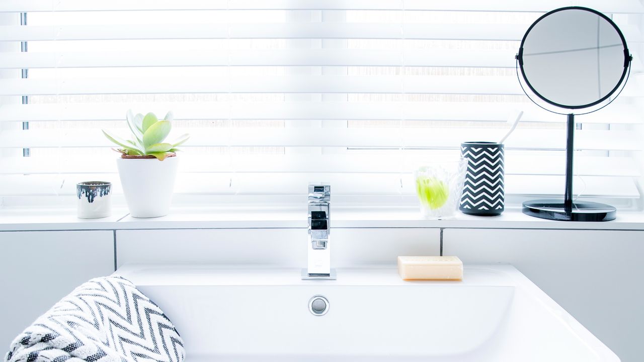 Bathroom sink with a magnifying mirror on a windowsill