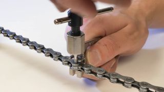 man using the park tool ct-5 chain tool to push out a chain rivet or pin