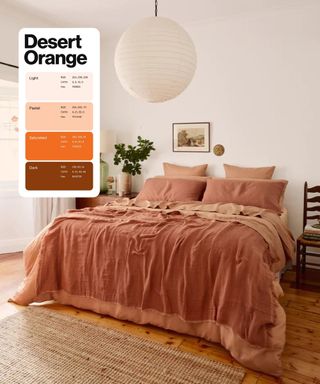 A large, airy, neutral bedroom with a terracotta, clay, and rose bedding, and a nightstand with eucalyptus greenery in a glass vase. Pinterest's Desert Orange swatch is an overlay