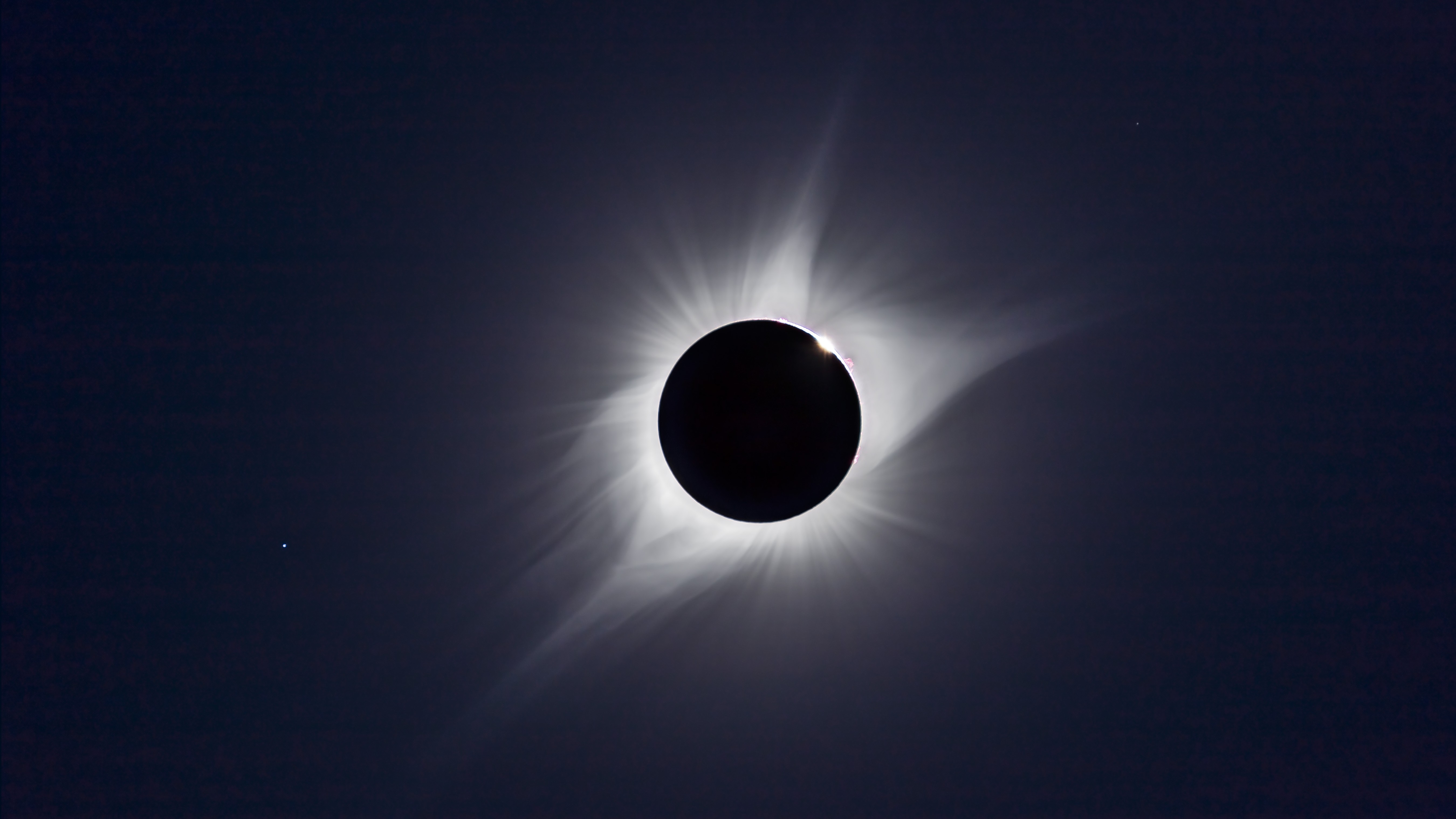 total solar eclipse whereby the sun is full covered by the moon and we see the white streamers of the sun's outer atmosphere, the corona.