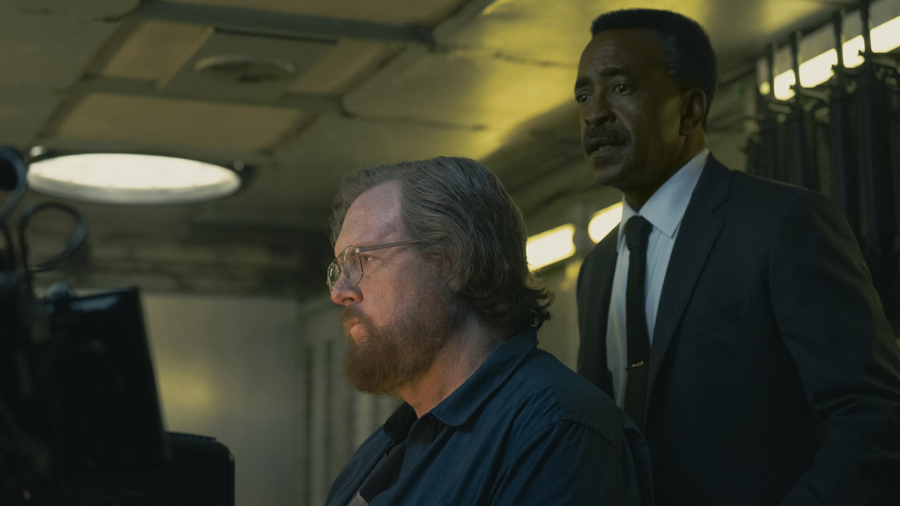 Langston Fleury standing over a seated John Economos in Peacemaker season 2