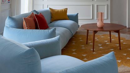 a blue sofa with rust throw pillows