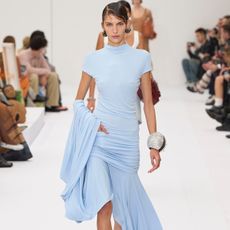 A model wears a blue draped maxi dress on the Acne Studios spring/summer 2025 runway