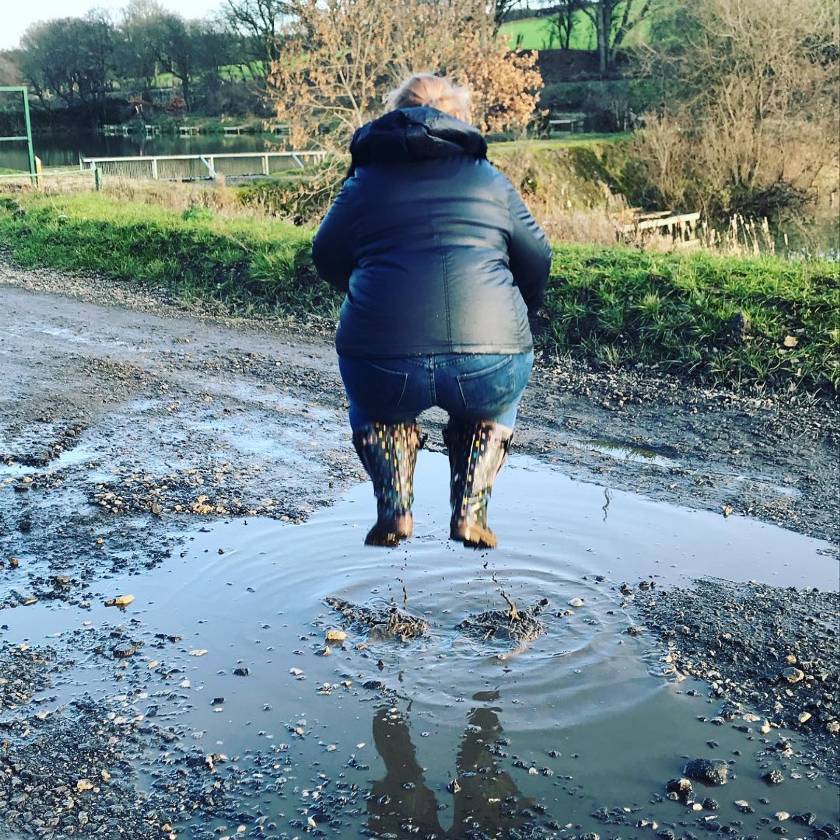 Lady jumping in a puddle wearing Jileon wellies