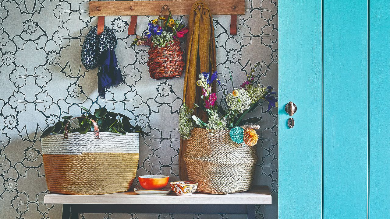 A hallway with a wall-mounted hook rack, a console table and a blue storage closet