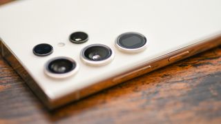 Et nærbilde av kameramodulen på baksiden av en hvit Samsung Galaxy S23 Ultra.