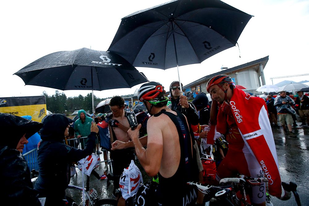 Riders seek relief from the rain after finishing stage 12.