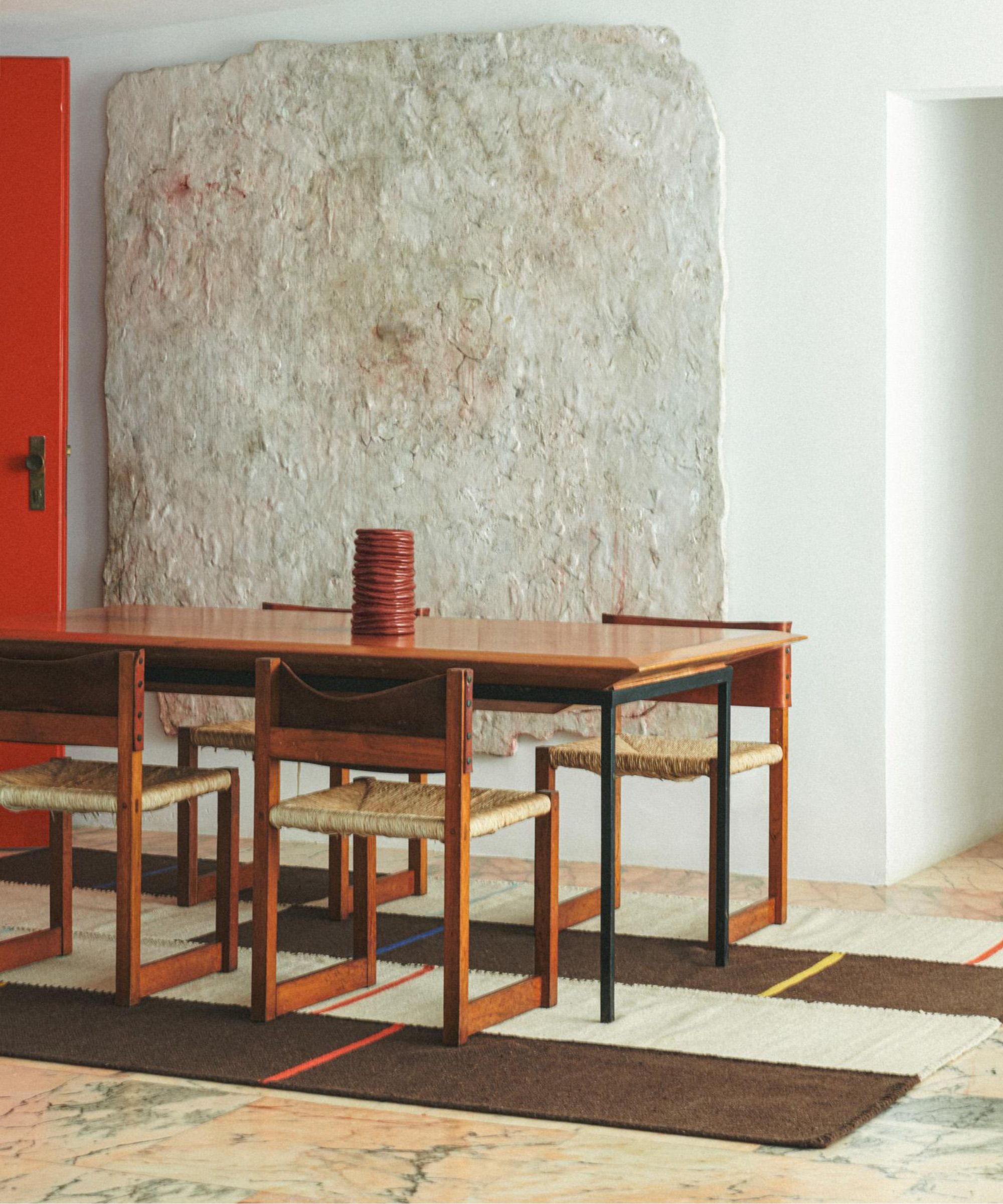 zara home x collagerie dining room with mid century wooden table and chairs and a brown and cream striped rug