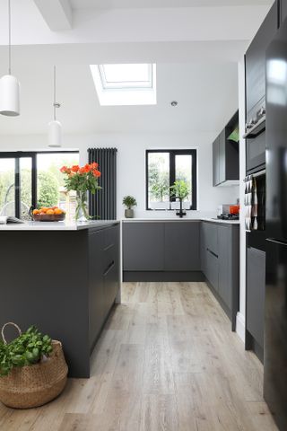 Black kitchen units, white worktop and wood-effect laminate floor