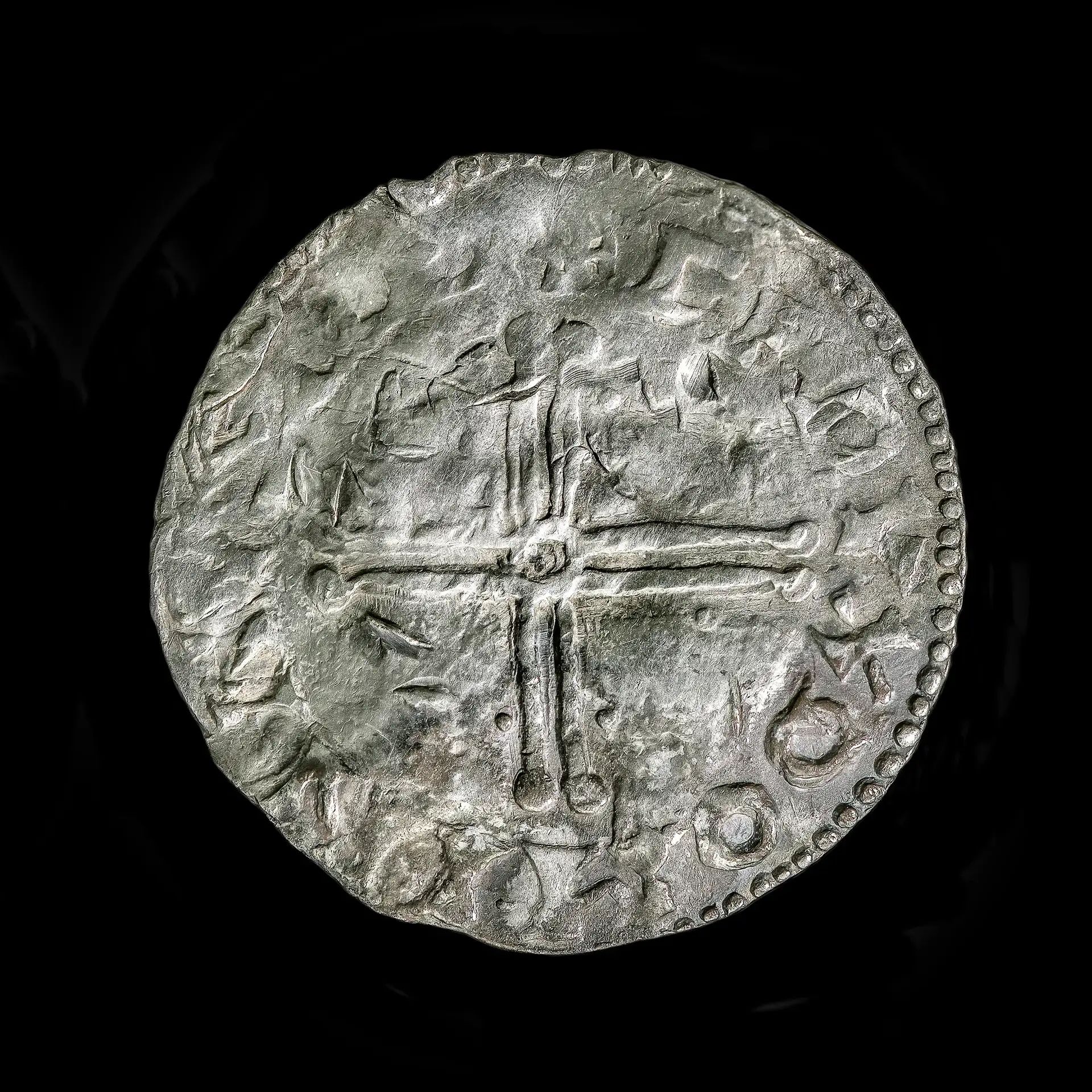 A close up of a silver coin showing a cross
