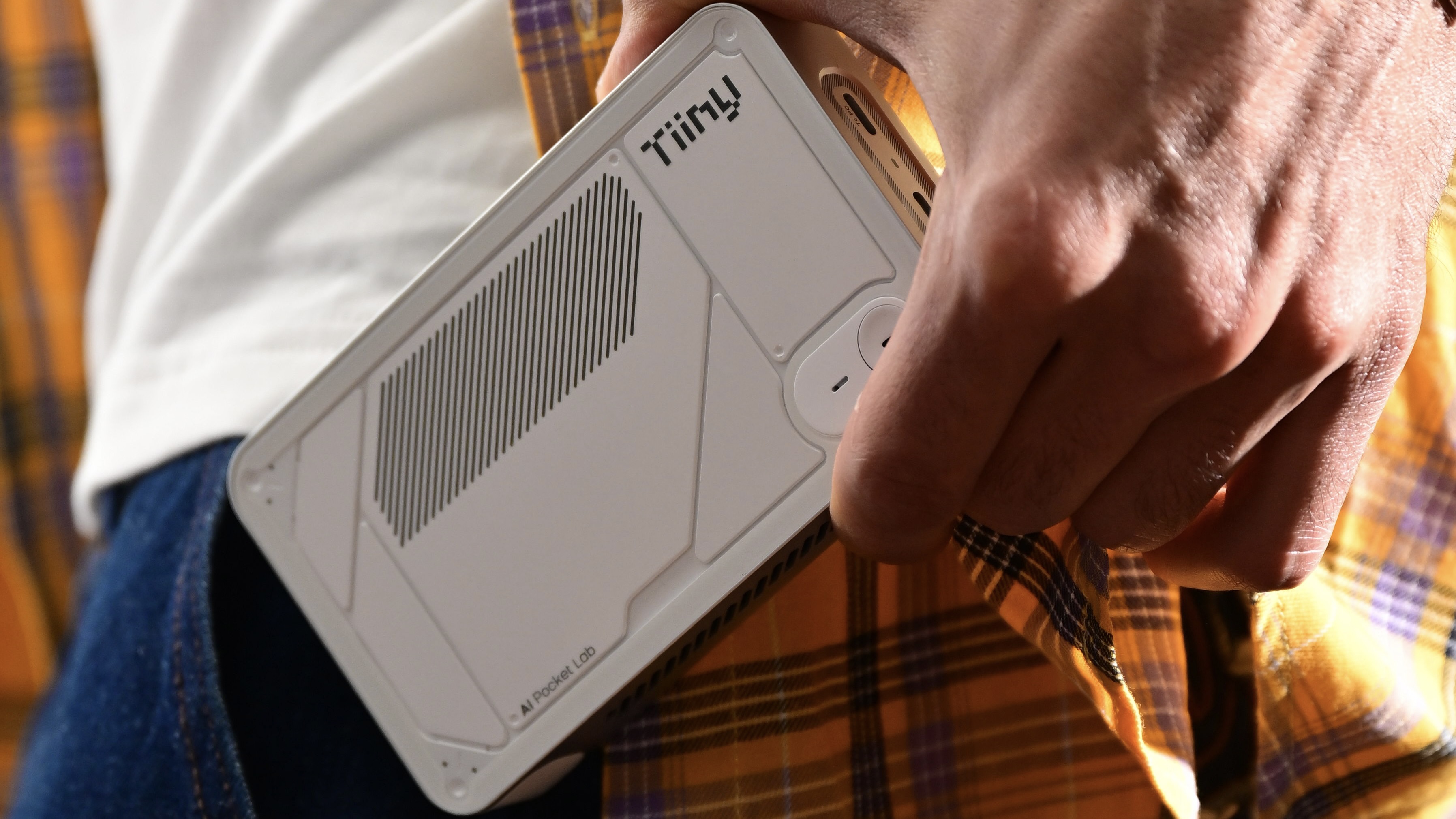 The Tiiny AI being held by a man and placed into his pocket.