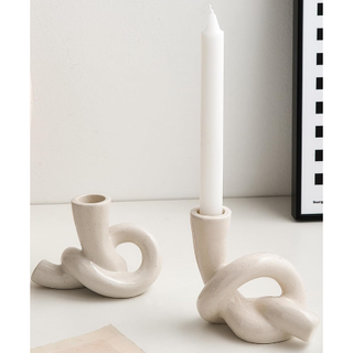 two stoneware candle holders in the shape of a knot