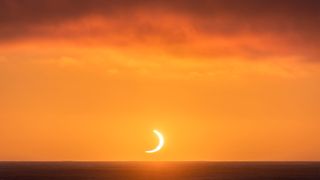 The sun looks like a crescent as part of the moon's dark umbral shadow takes a "bite" out of it on Dec. 4, 2021.