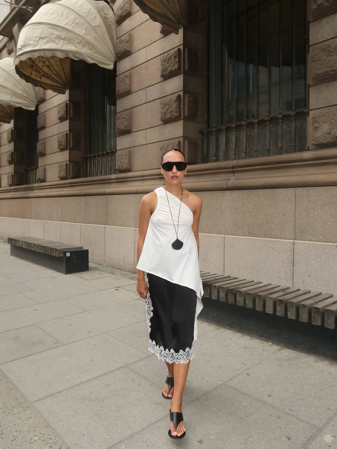 Woman in a white asymmetric top and lace-trim skirt.