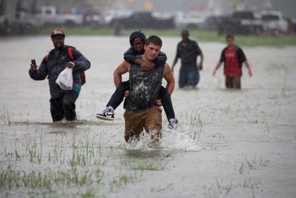 A man wades through flood waters from Tropical Storm Harvey while helping evacuate a boy in east Houston, Texas.