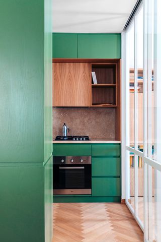 green kitchen cabinets and a glass partition wall with white framing