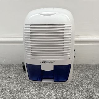 The white and purple ProBreeze 1500ml Mini dehumidifier on a speckled grey carpet