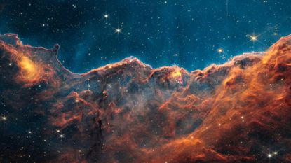 orange clouds of dust in space look like mountains in the JWST image