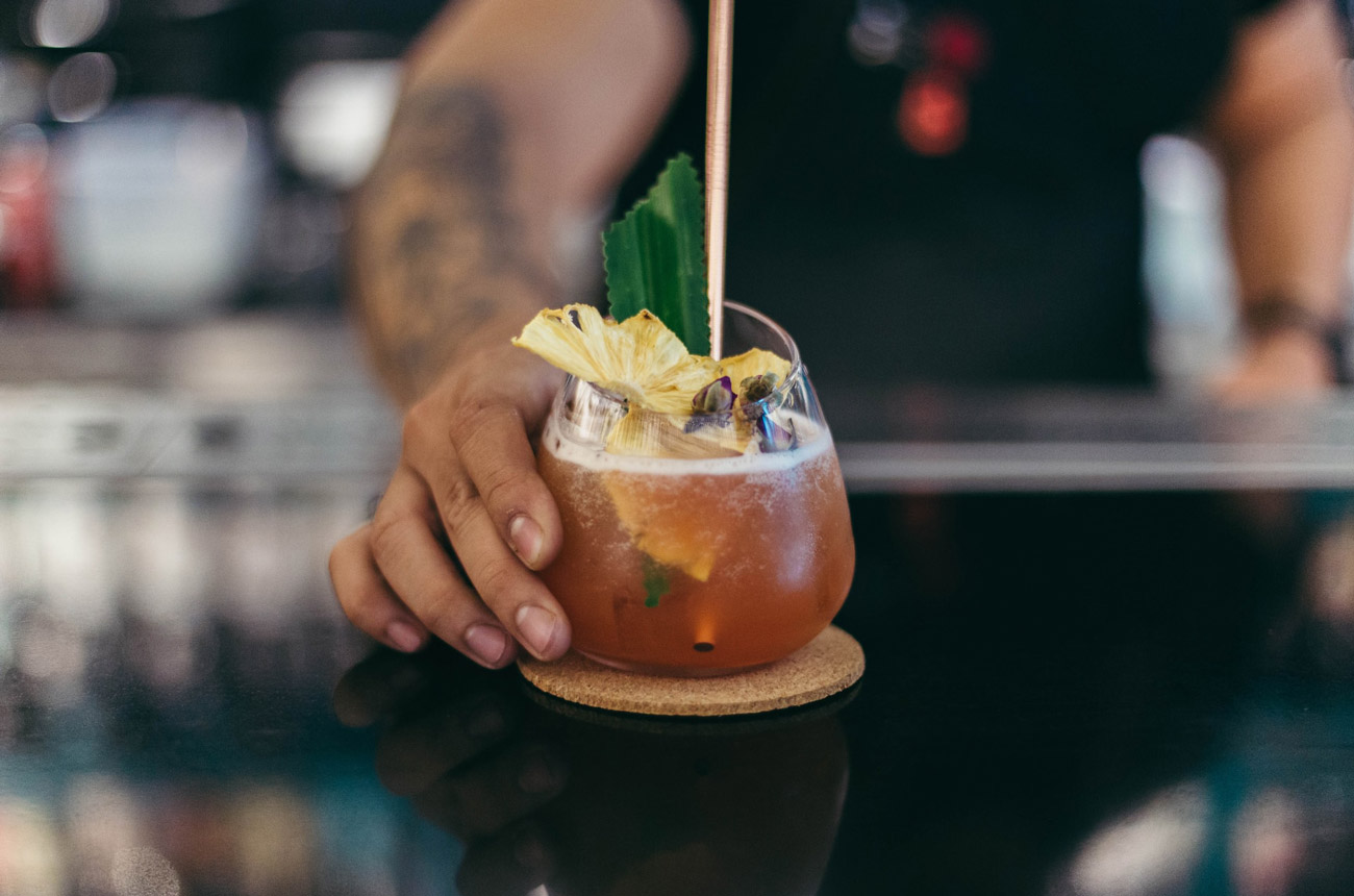 Hand holding a rum cocktail on a bar