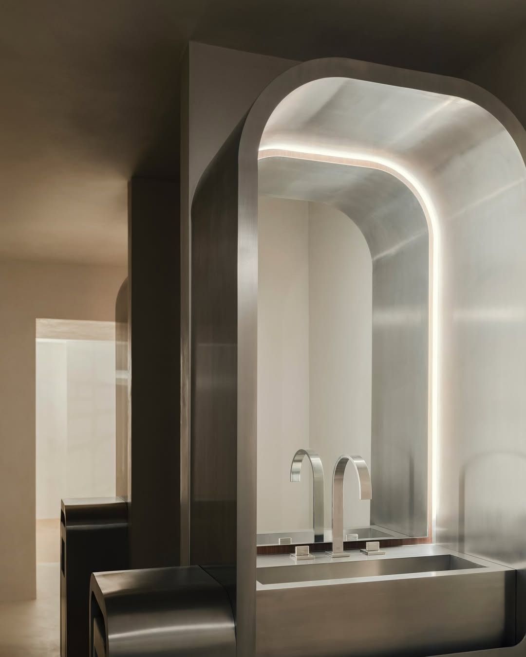 A chrome-clad apartment, featuring atmospheric cold lighting, brushed steel surfaces, and a pared back design scheme.