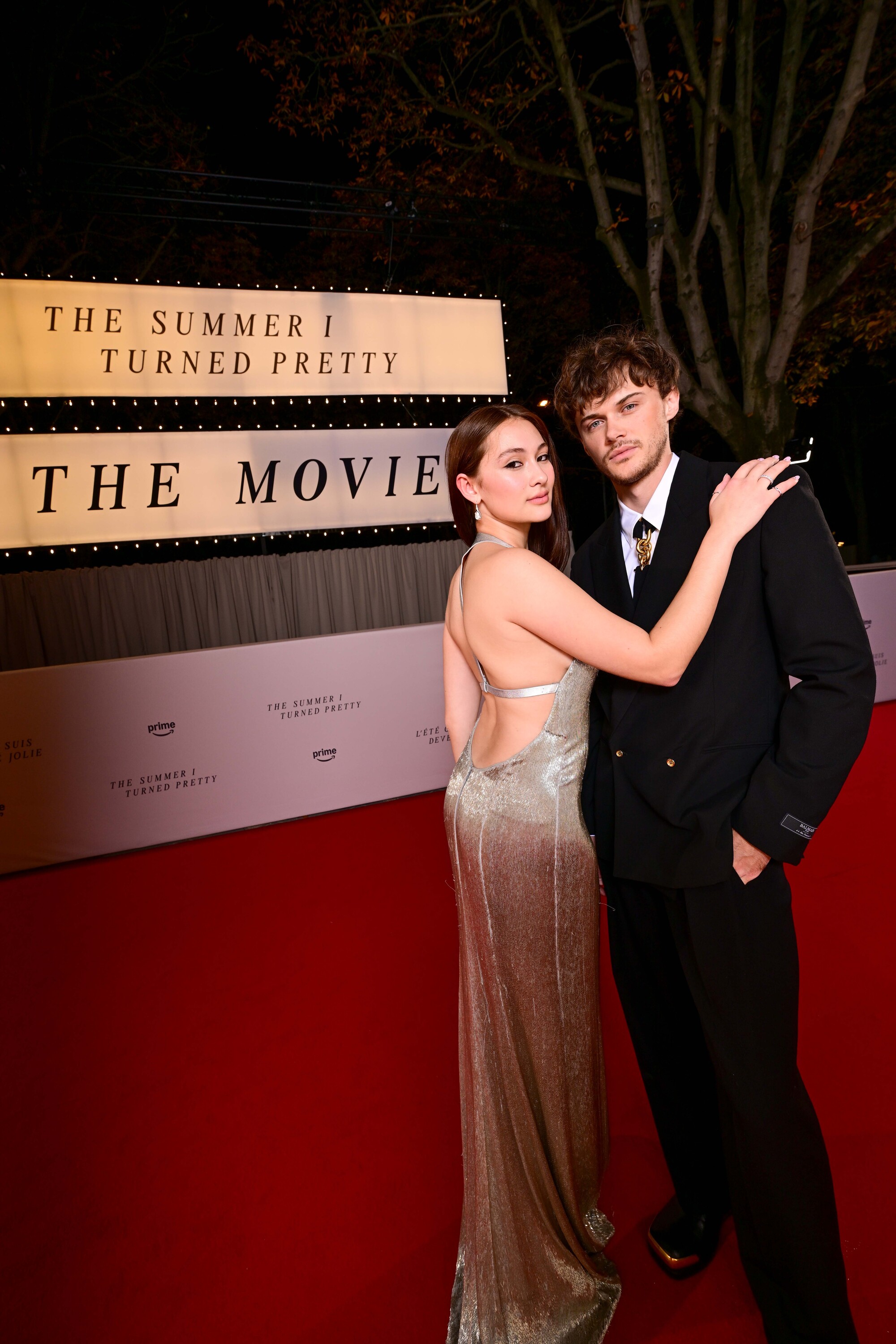 Lola Tung and Christopher Briney pose next to a sign reading &#039;The Summer I Turned Pretty: The Movie&#039;