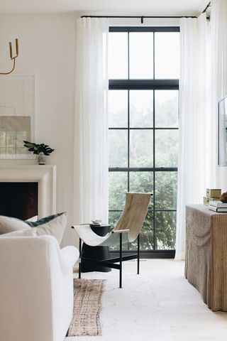 neutral living room with steel-frame windows, cream sofa and statement armchair