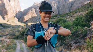 Woman checking sports watch on mountain trail