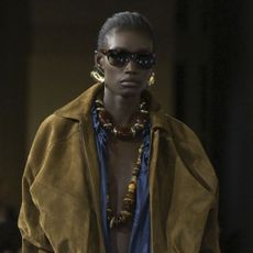 A Saint Laurent model wearing gold earrings and chunky beaded necklaces