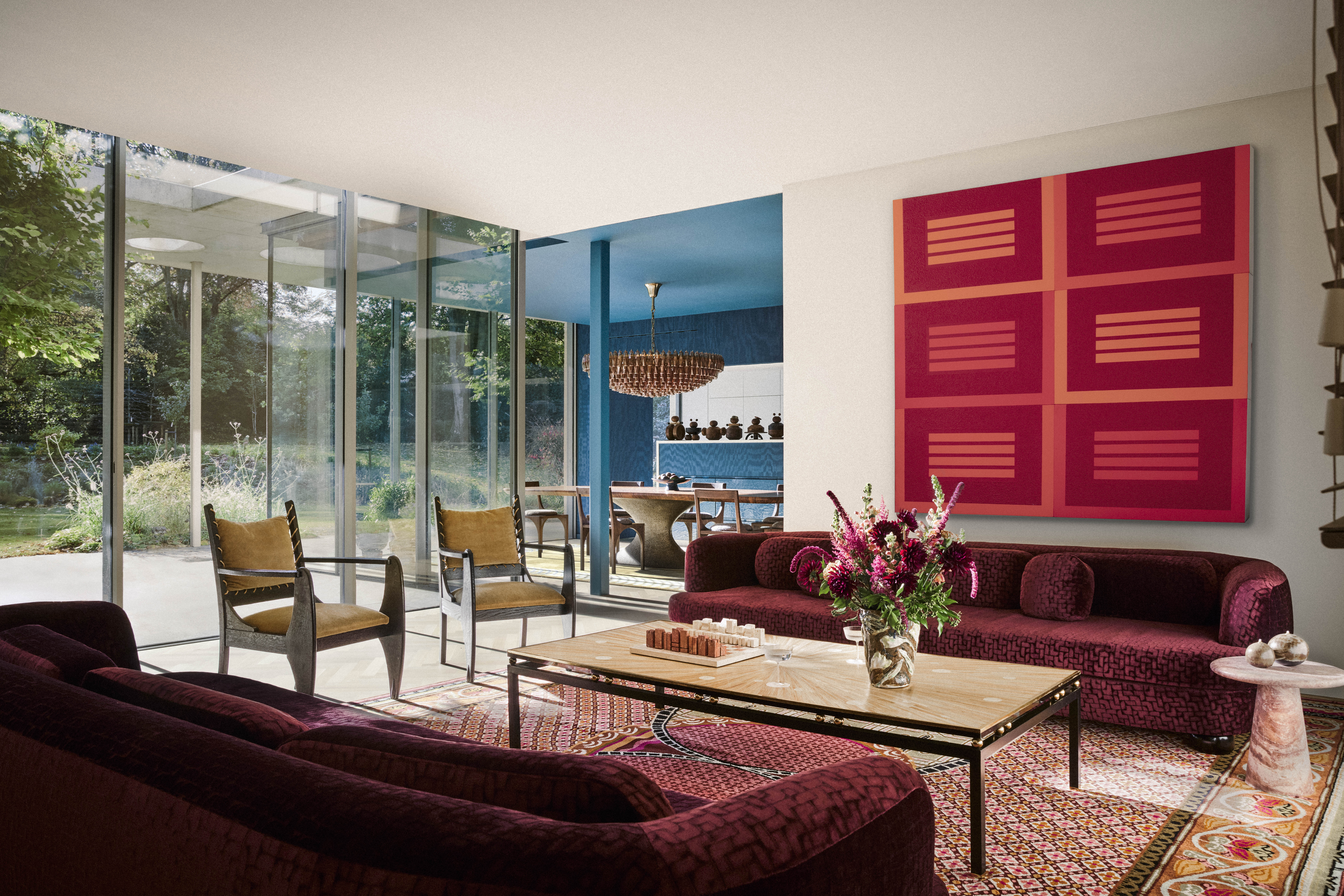 A living room with a large red artwork on the walls, red sofas, and large windows