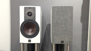 Dali Rubikore 2 standmount speakers from front against grey wall one with grille in place