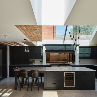 view into a kitchen with a large kitchen island, range cooker and large overhead glazing