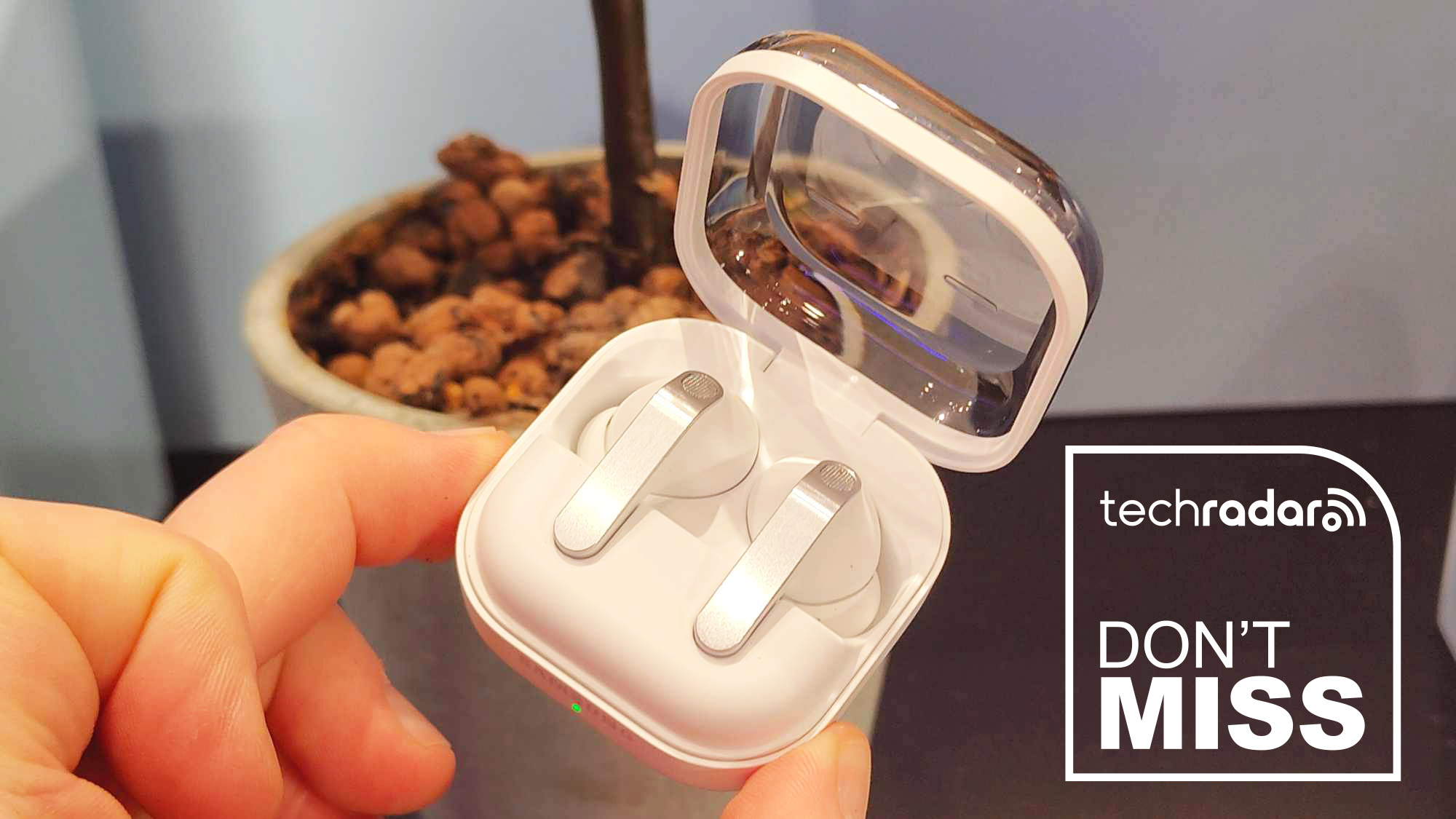 White Samsung Galaxy Buds4 Pro earbuds in their case and held in a hand, with "Don't Miss" text in white.