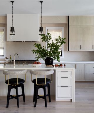 kitchen with white and pale wood units and black bar stools