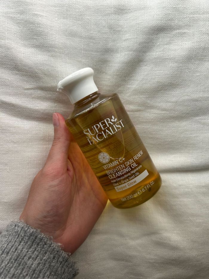 Junior beauty editor Grace Lindsay holding the Super Facialist Vitamin C+ Skin Renew Cleansing Oil