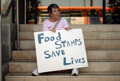 A woman holds a sign for food stamps