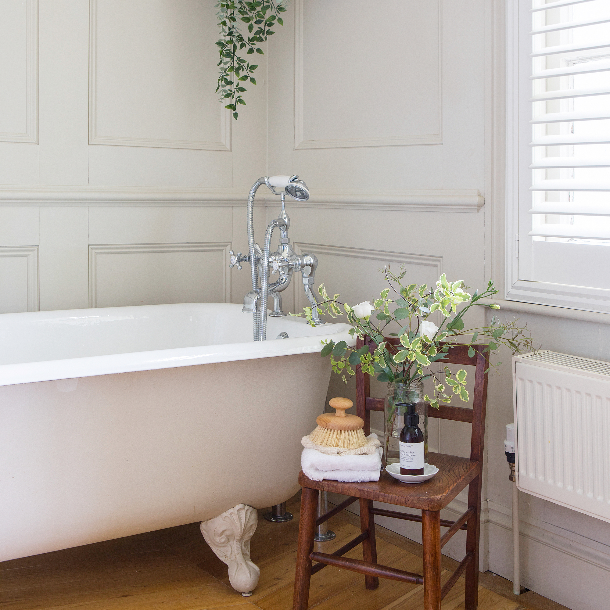 a bathroom with wooden panelling and a claw-footed roll top bath