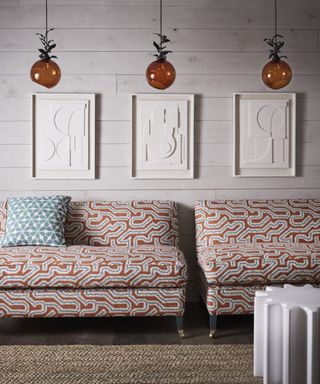 pair of orange patterned banquet seats with white artwork and orange glass pendant lights