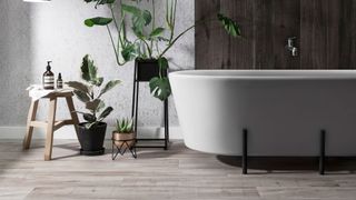 Bathroom trend with wood-effect floor and wall tiles, contemporary freestanding white bath on black metal feet and lots of plants