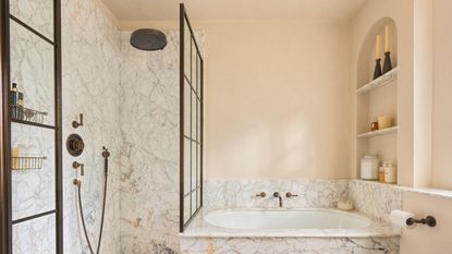 A small bathroom with a mini tub, a shower cubicle, and an arched shelving nook
