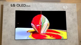 De LG G3 OLED hangt aan een grijze muur en vertoont een abstracte afbeelding met rode en gele verf