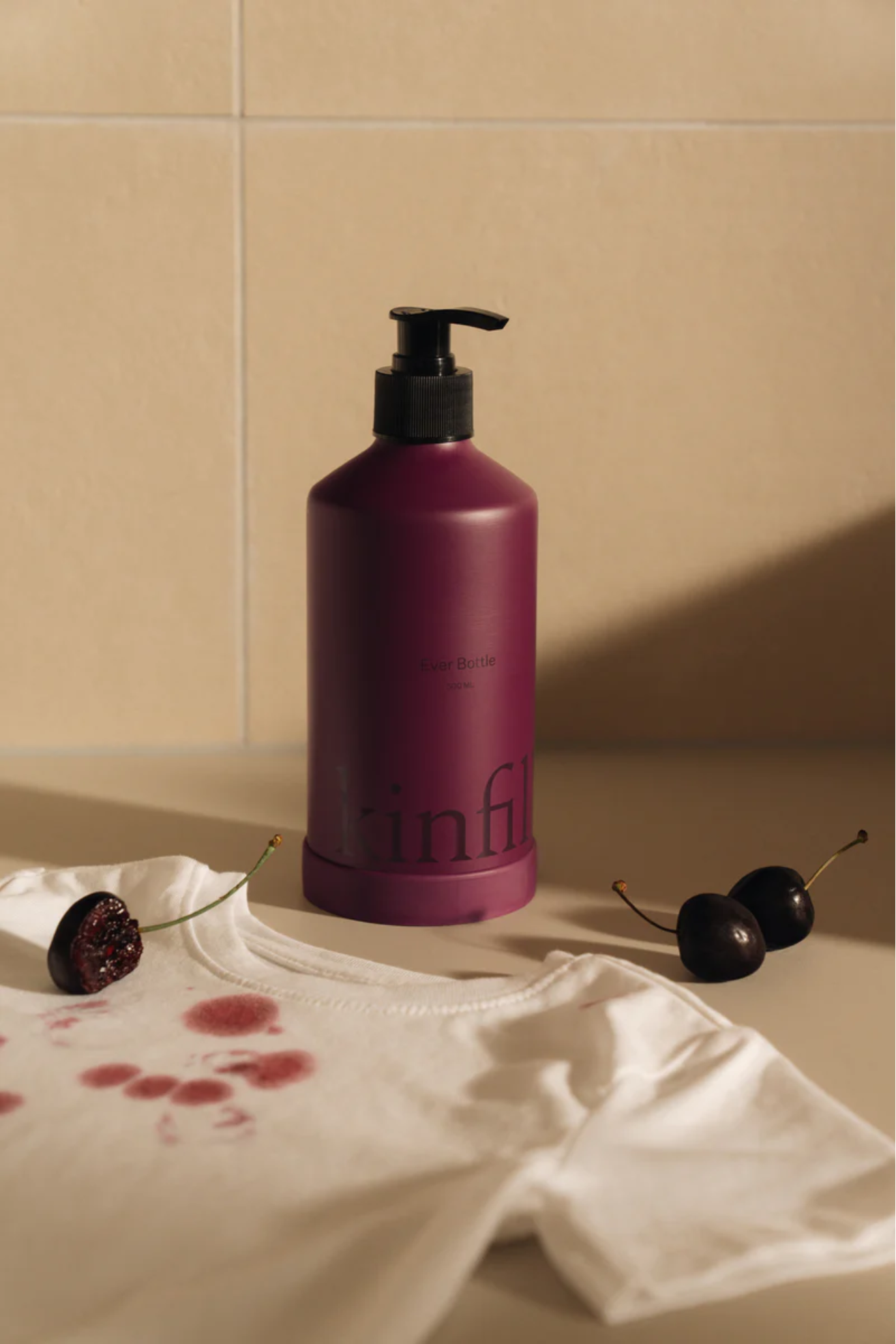 A burgundy bottle of laundry detergent against a light yellow background