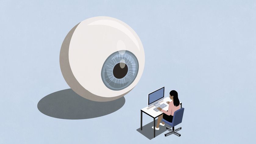 Large blue eyeball watching businesswoman working at computer