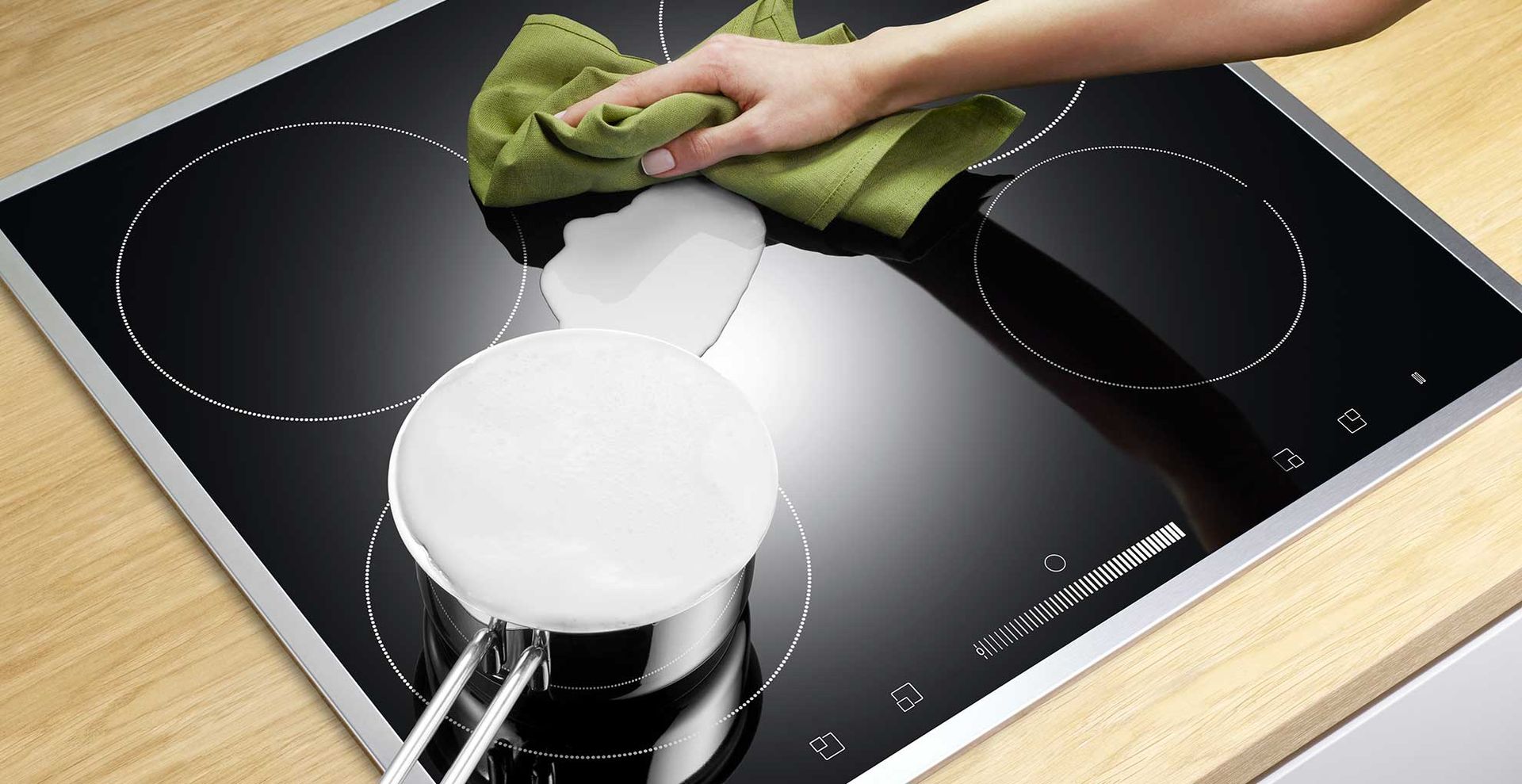 black induction hob with a saucepan of milk overspilling